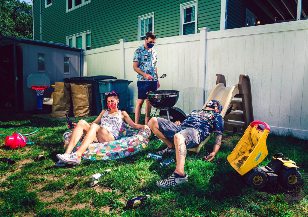 Boston melodic punk band The Jacklights lounge around (masked) in a backyard by grilling, sitting in a kiddie pool with a beer, and lying sprawled out on a children's slide
