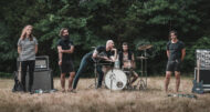Post-hardcore band Dreamwell stands in a horizontal line, with a drumkit in the center, in the middle of an open field