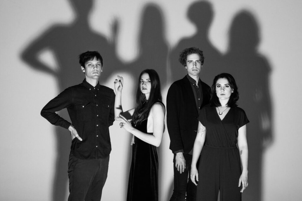 Brooklyn band Activity posing together side-by-side in black and white, with tall shadows of each of the four members cast behind them.