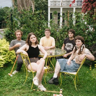 The band Wednesday posing around some outdoor patio furniture