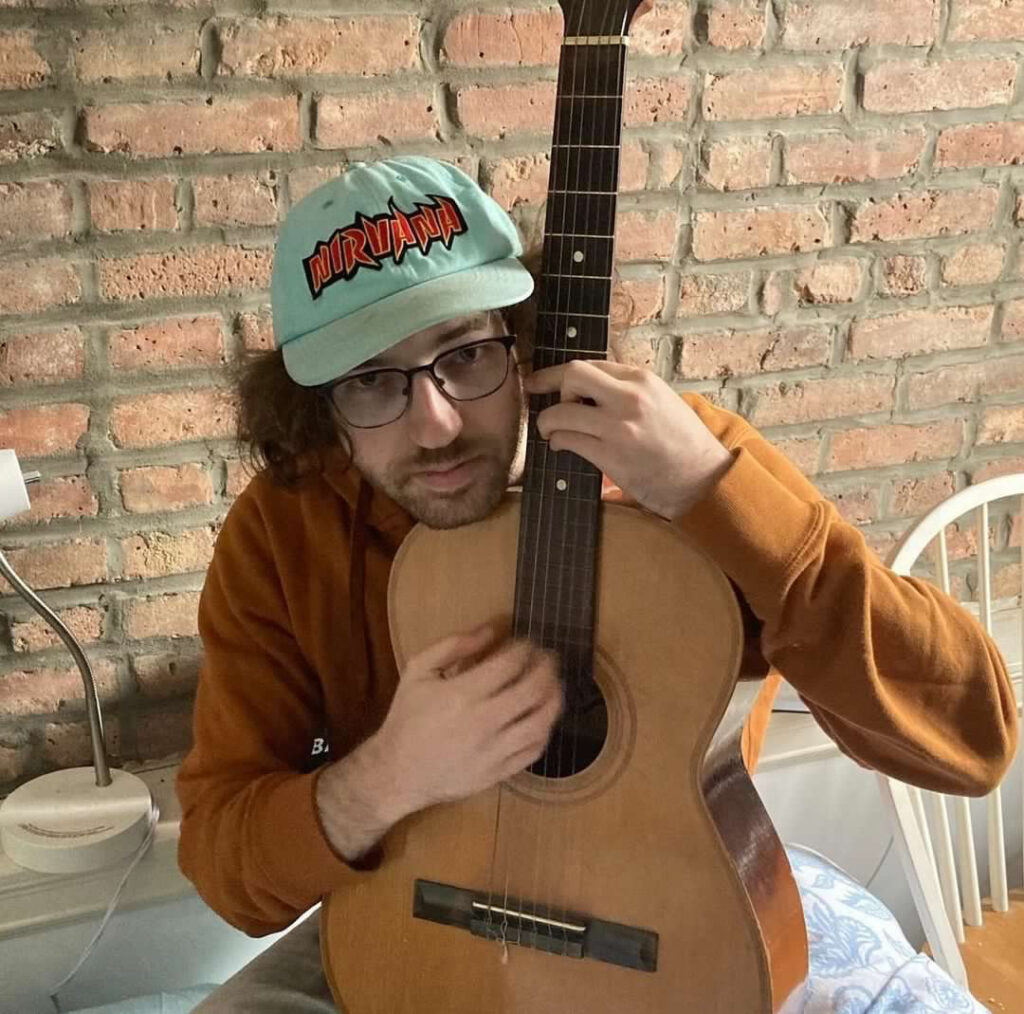 DJ Silky Smooth posing in a room with a classical guitar