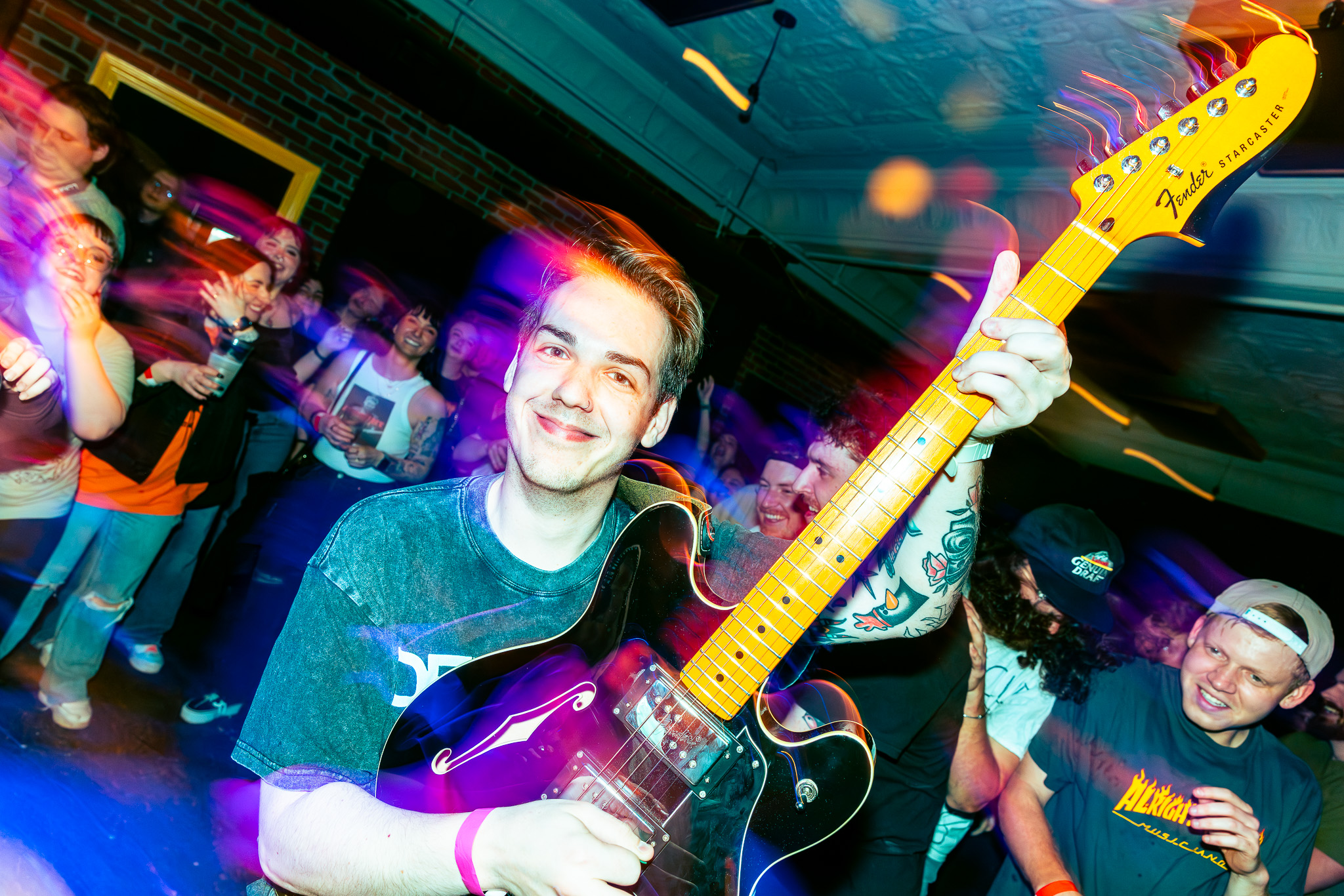 Cam Cavagnaro smiles at the camera while playing his guitar in the pit