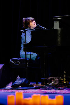a woman sings into a microphone while playing piano