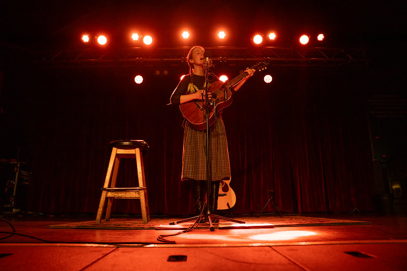 margaret glaspy performing with an acoustic guitar on an orange lit stage
