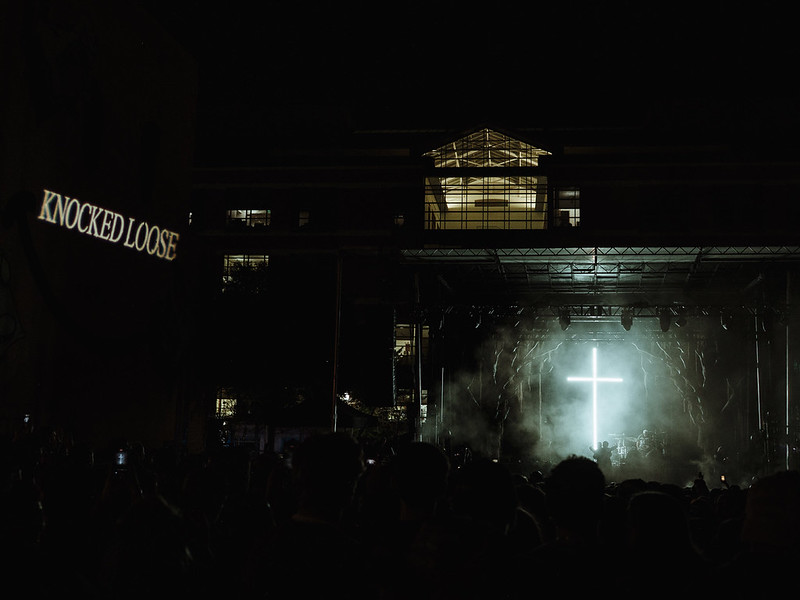 knocked loose perform in almost complete darkness with a giant lit up cross behind them on stage